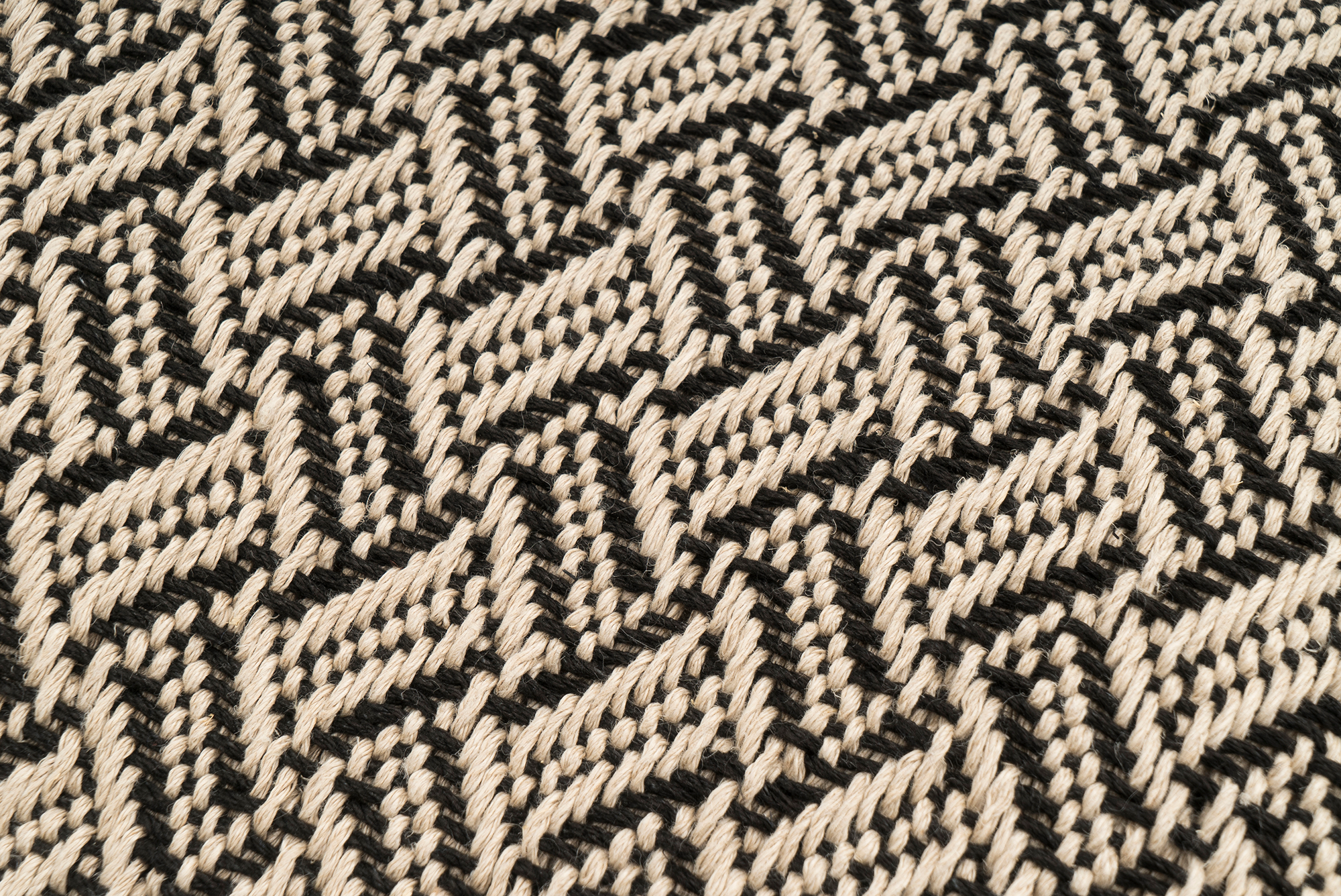Sustainable hemp pillow cover, handwoven with chevron and herringbone motifs, beige and black.